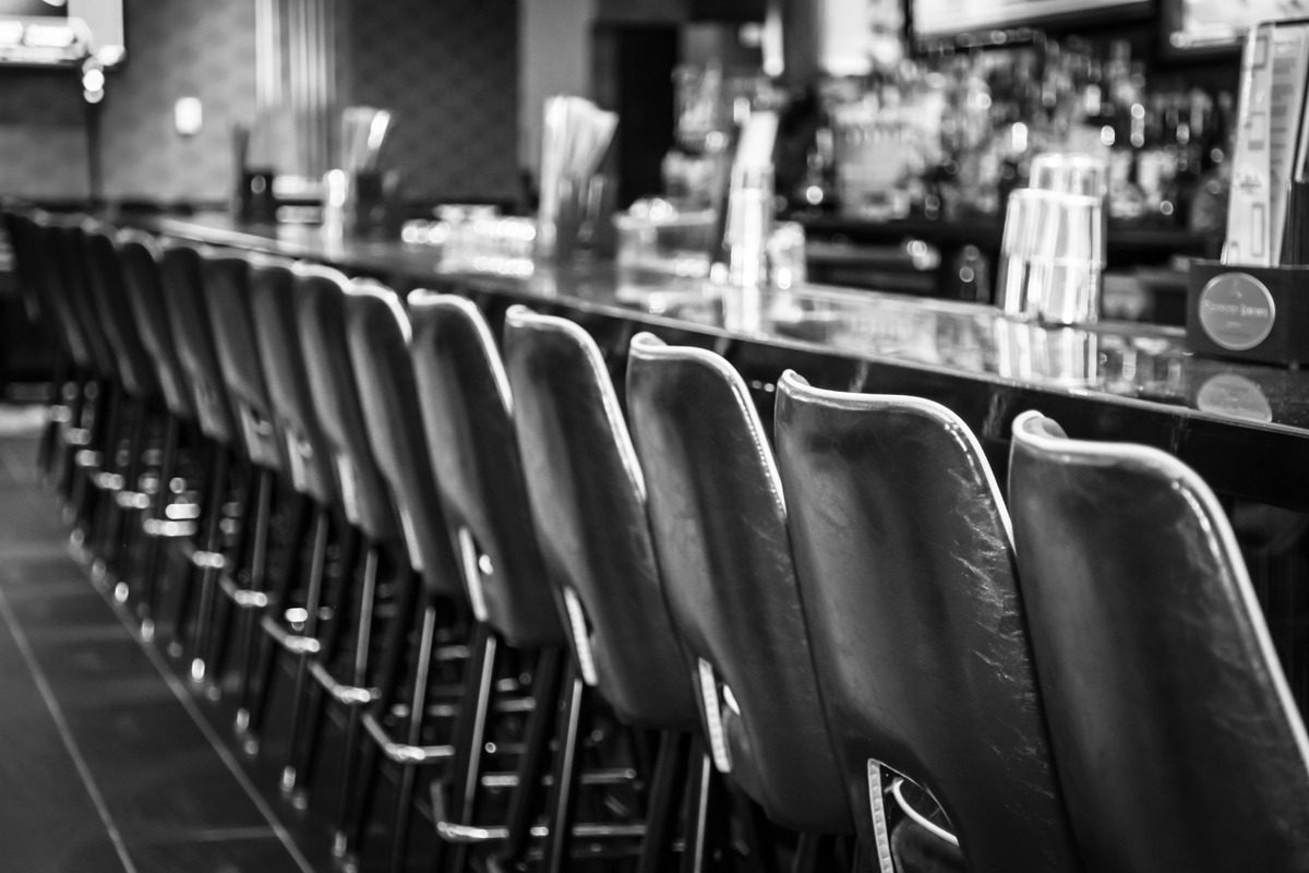 Empty bar stools lined up at a classic bar counter.