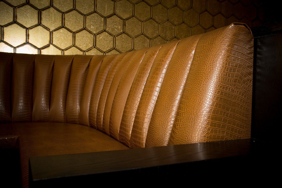 Close-up of a padded, honeycomb-patterned brown leather bench seat.