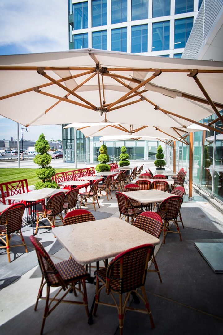Outdoor café seating with tables and chairs under large umbrellas.