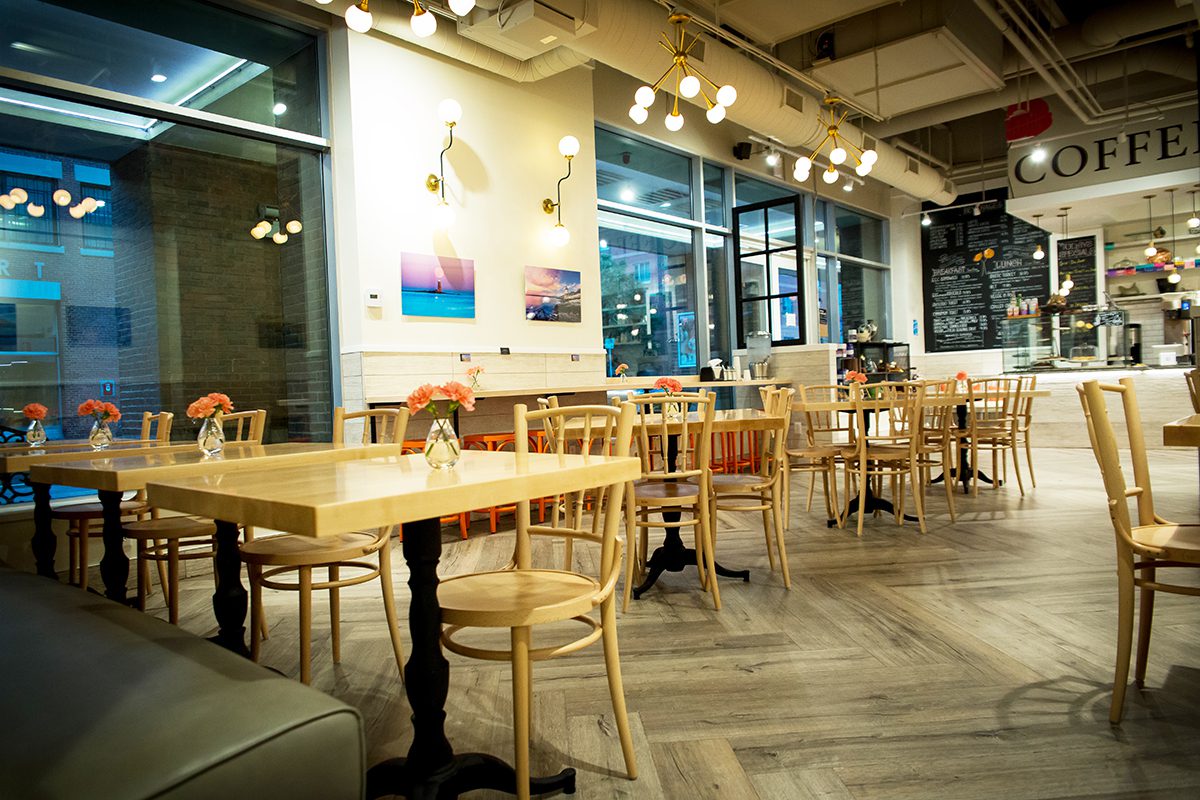Cozy, well-lit café with wooden tables and chairs in a modern setting.