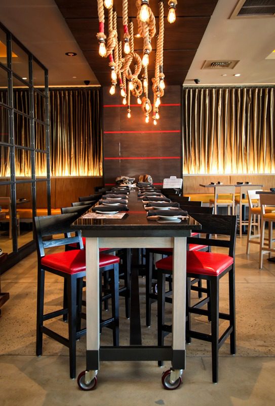 Elegant restaurant interior with warm lighting and red-cushioned chairs.