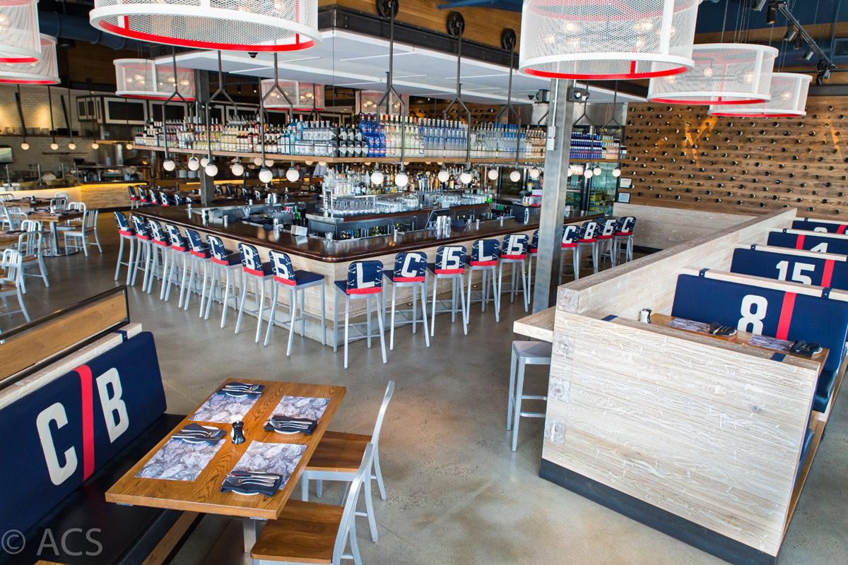 Modern bar with high stools and neatly arranged tables in a spacious setting.