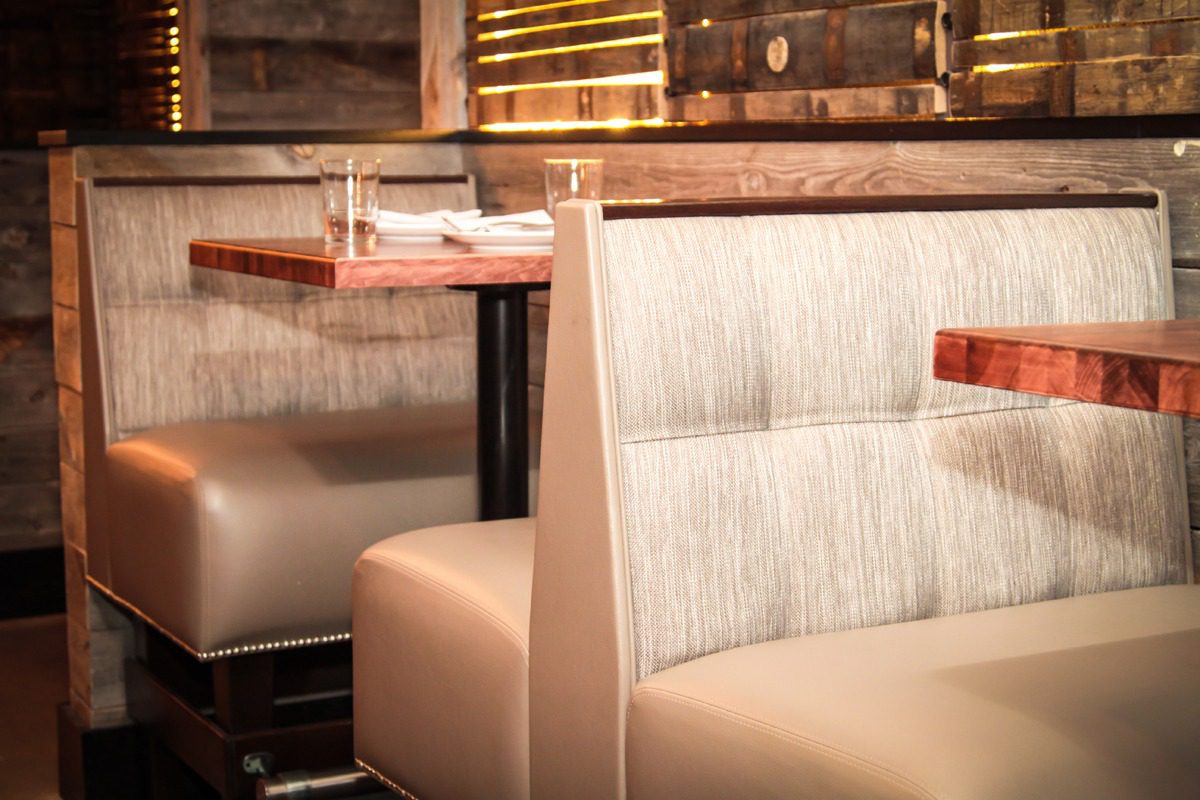 Cozy booth seating with beige cushions and wooden shelves in a warm-lit restaurant.