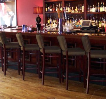 Empty bar stools lined up at a cozy wooden bar.