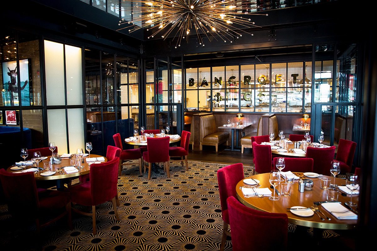 Elegant dining room with red chairs and warm lighting.
