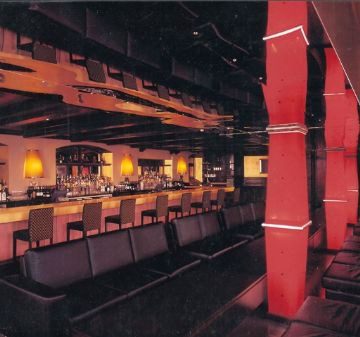 Dimly lit bar with wooden decor and seating at the counter.