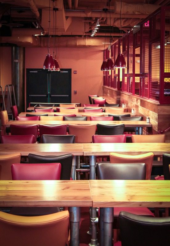 Empty restaurant dining area with wooden tables and chairs.