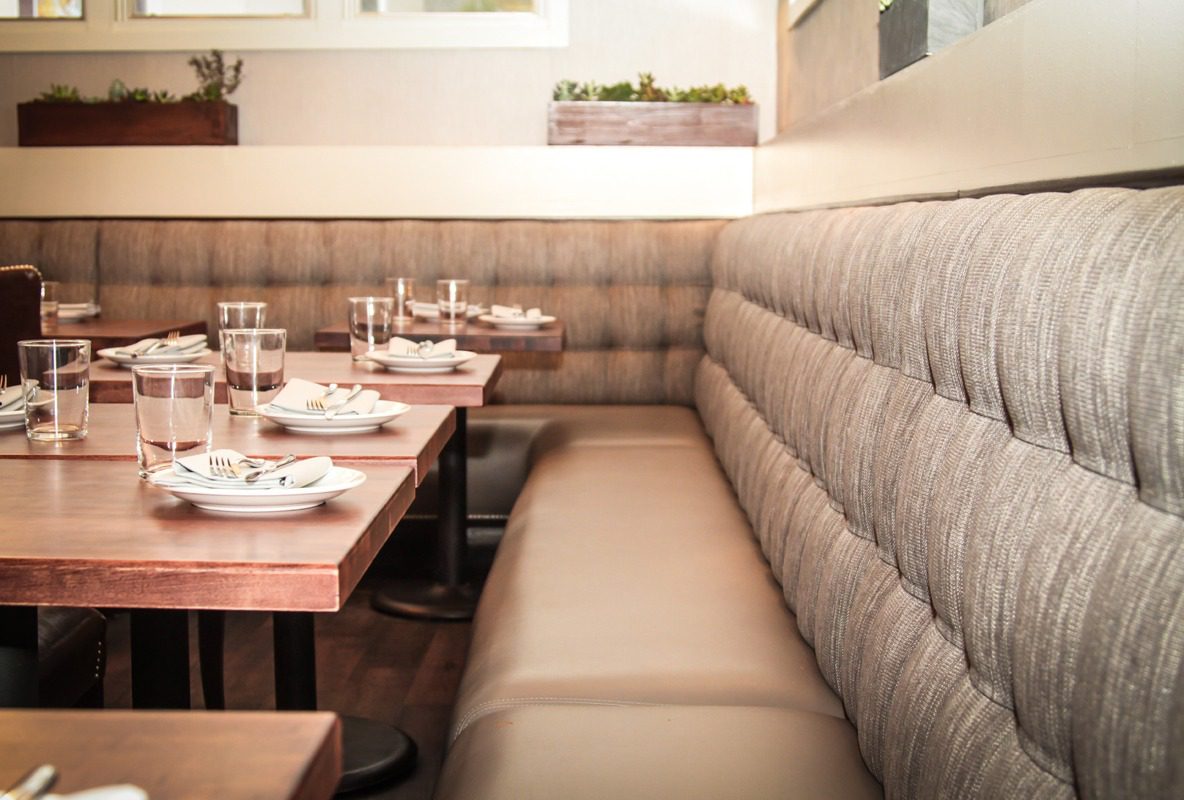 Cozy restaurant booth seating with tufted cushions and neatly set tables.
