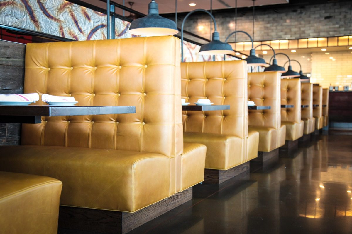 Empty yellow booths line a modern restaurant interior.