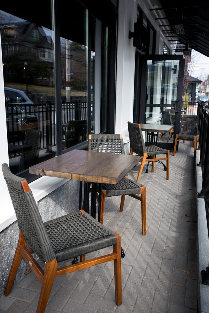 Cozy outdoor café seating with wooden tables and woven chairs.