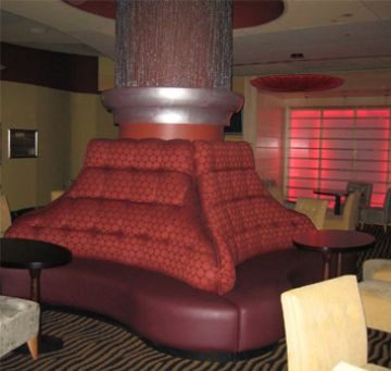 Unique pyramid-shaped seating area with red upholstery in a lounge.