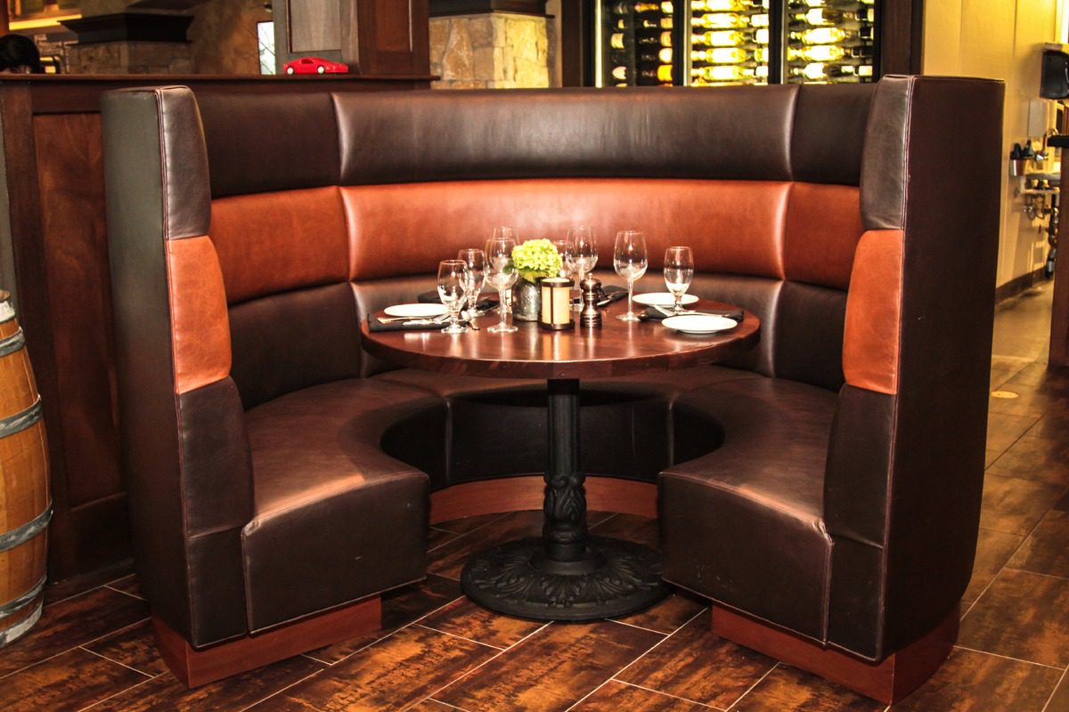 Cozy leather booth seating around a round table in a warm restaurant setting.
