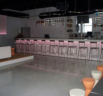 Modern bar with high stools and ambient lighting.