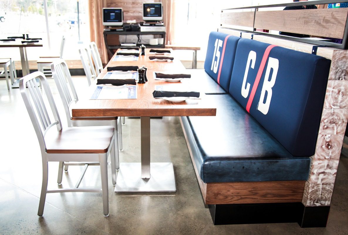 Modern restaurant seating with wooden tables and cushioned bench.