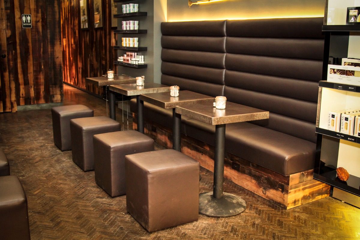Modern café seating with cushioned stools and wooden tables in a cozy ambiance.