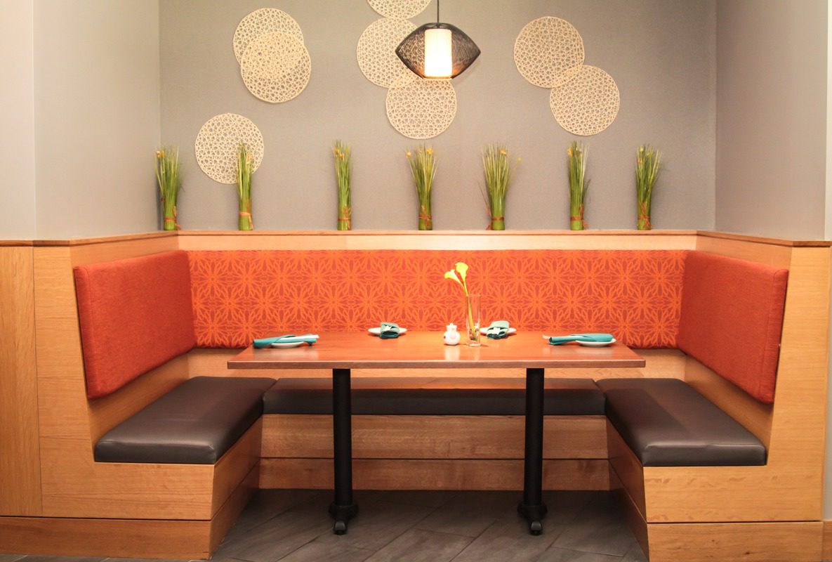 Cozy restaurant booth with orange seating and soft lighting.