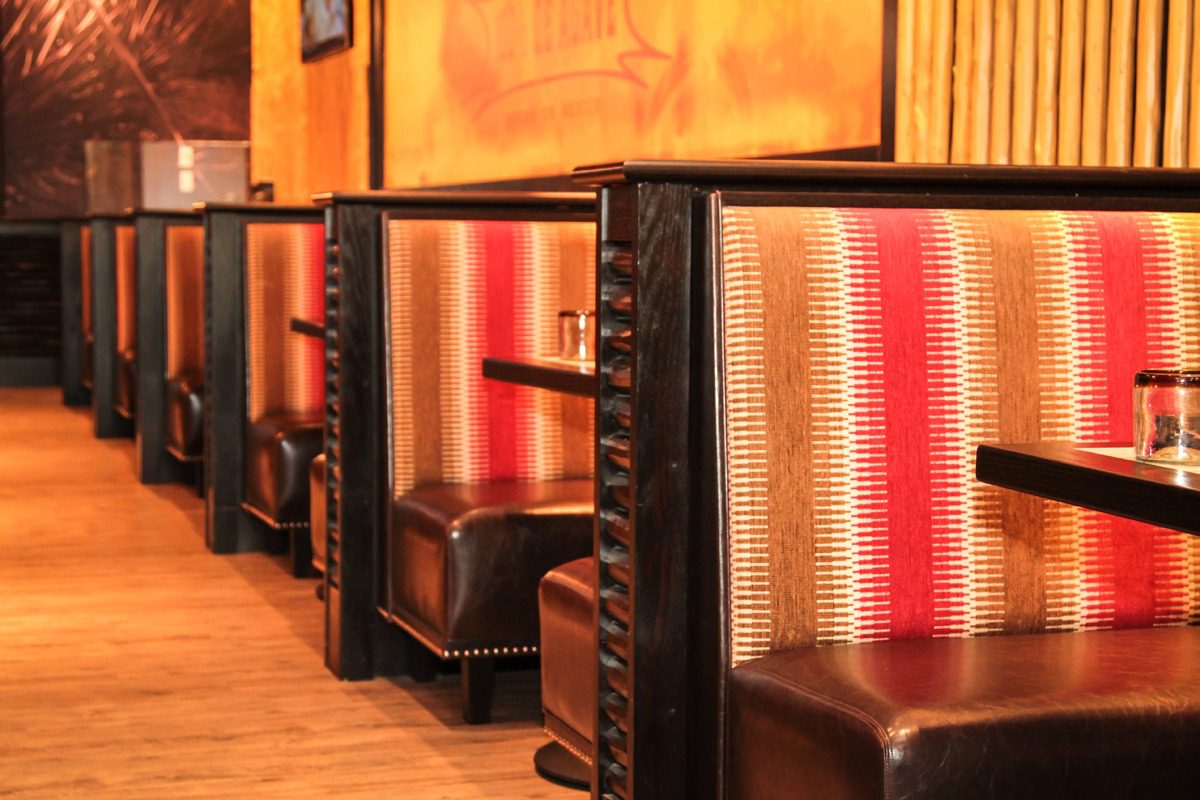 Cozy restaurant booths with leather seats and patterned fabric backs.