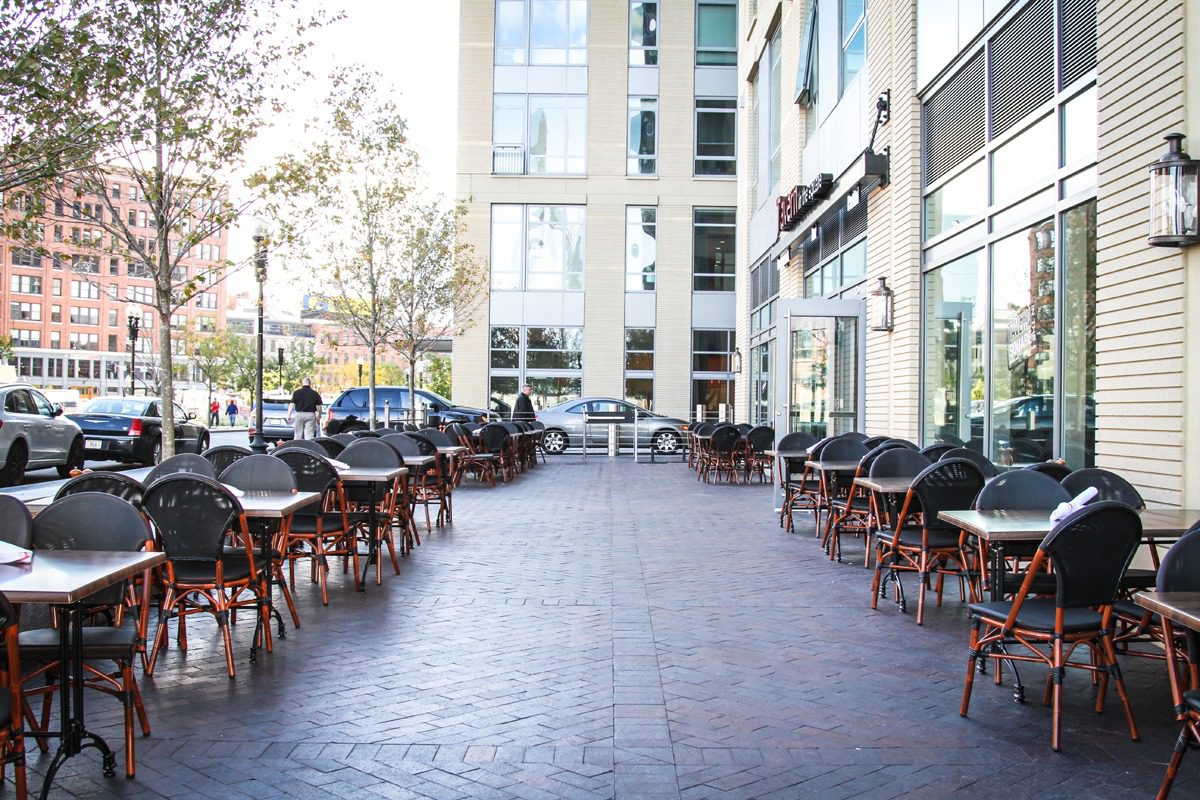 Outdoor seating area of a modern cafe with empty tables and chairs.