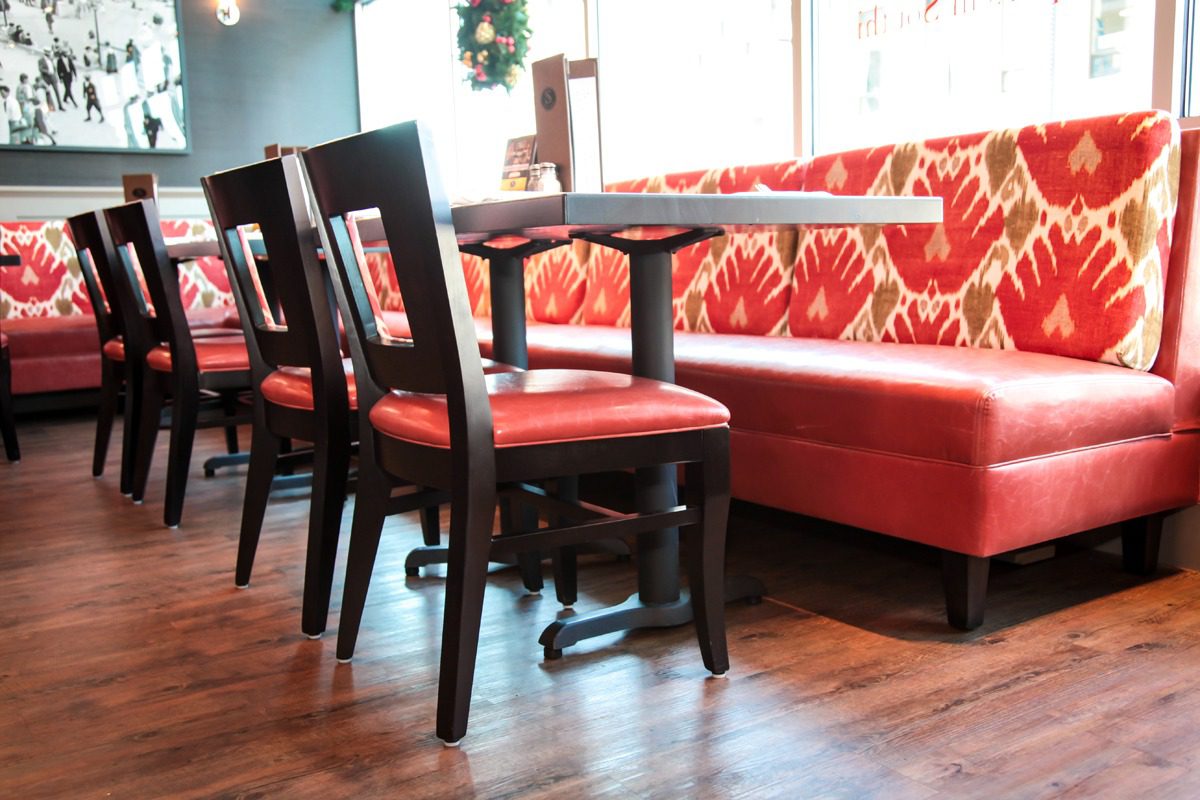 Elegant dining chairs with red cushions and a matching red booth seating.