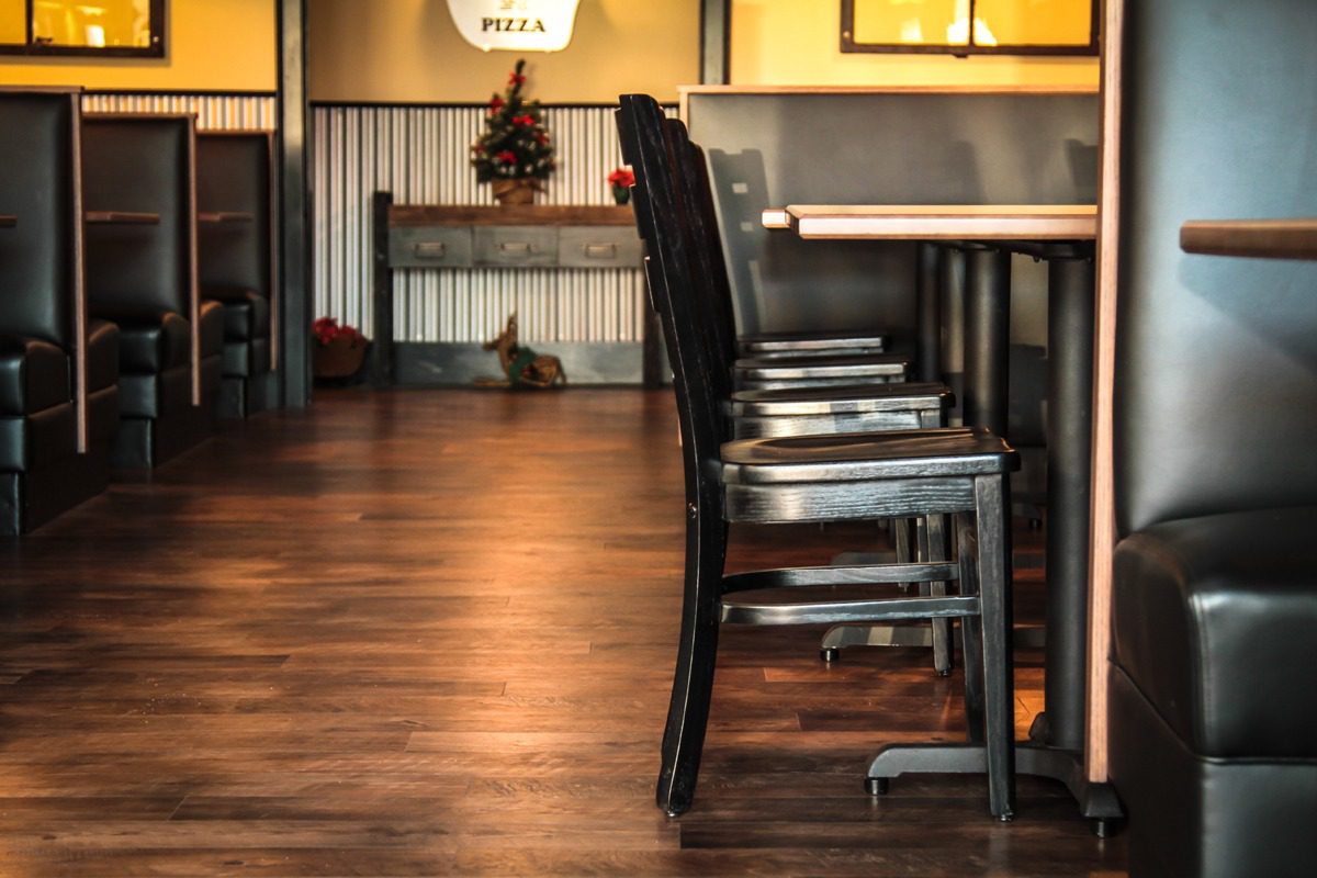 Empty wooden chairs lined up along tables in a cozy restaurant.