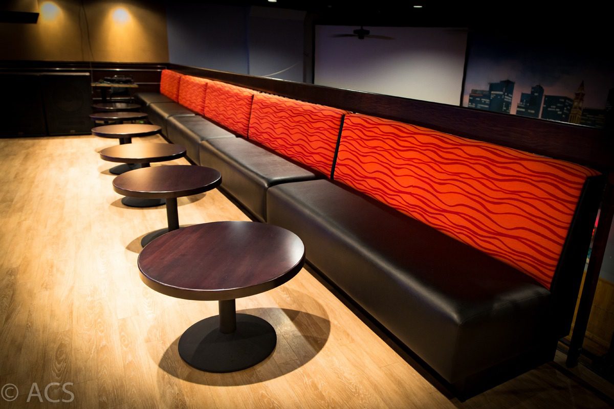 Modern lounge seating with vibrant red cushions and round tables.