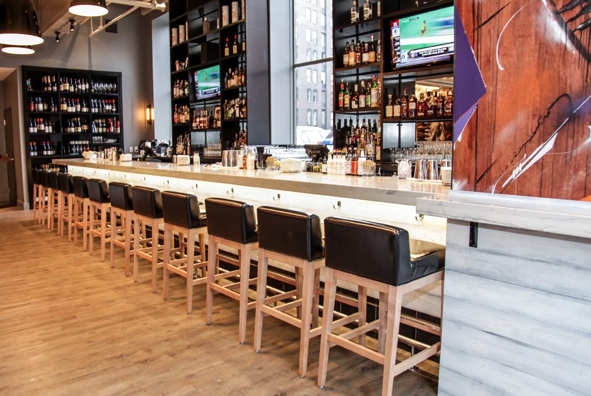 Modern bar with wooden stools and a marble countertop.