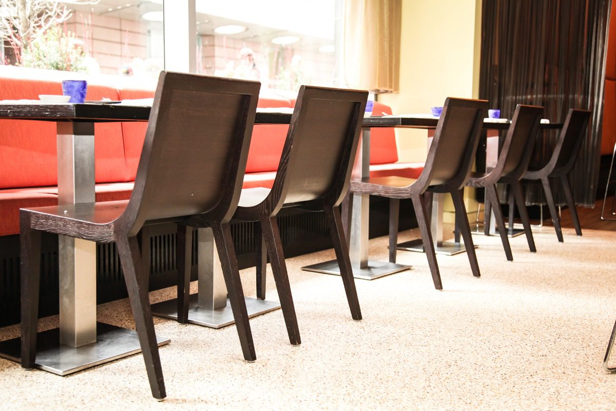 Row of wooden chairs lined up indoors near a window.