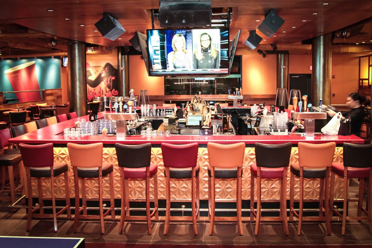 Cozy bar with wooden stools and multiple TVs showing sports.