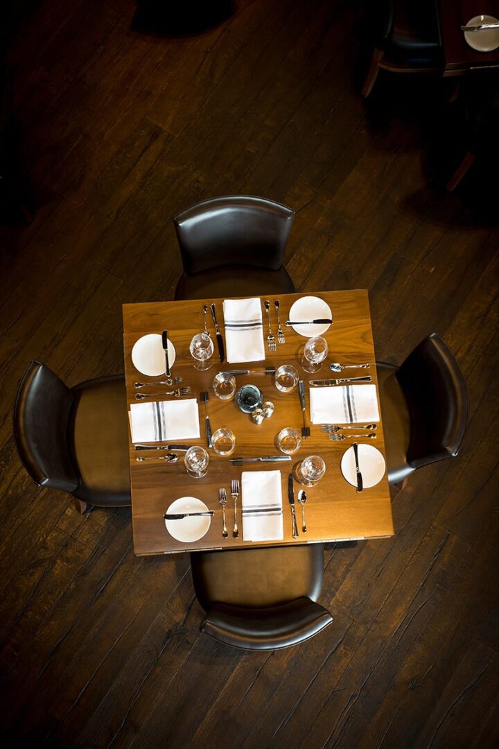 Top view of a wooden dining table set for four with plates and glasses.