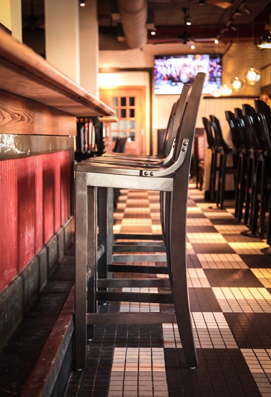 High chairs lined up at a bar with warm lighting.