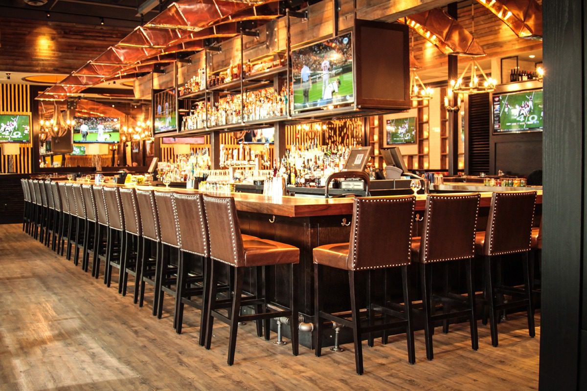 Cozy bar with high chairs and warm lighting.