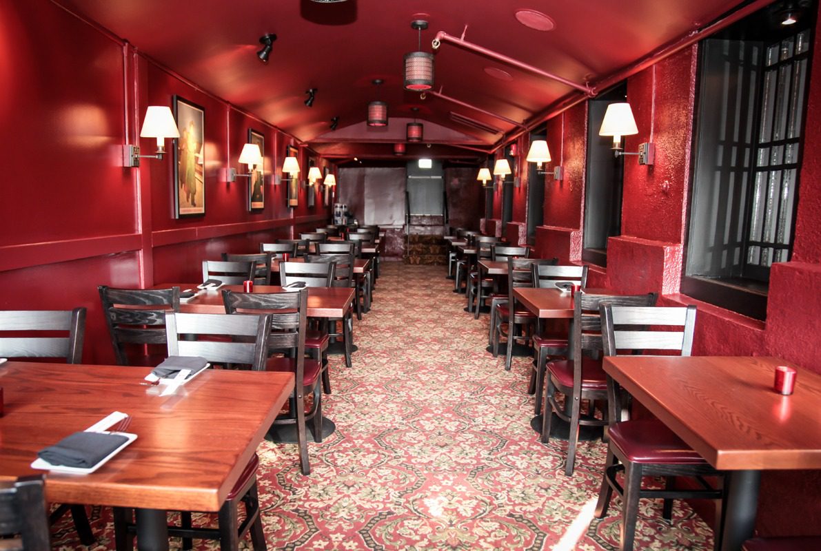 Inside a vintage red train dining car with elegant wooden tables and chairs.