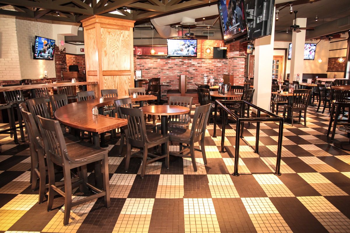 Cozy restaurant interior with wooden tables and checkered floor tiles.