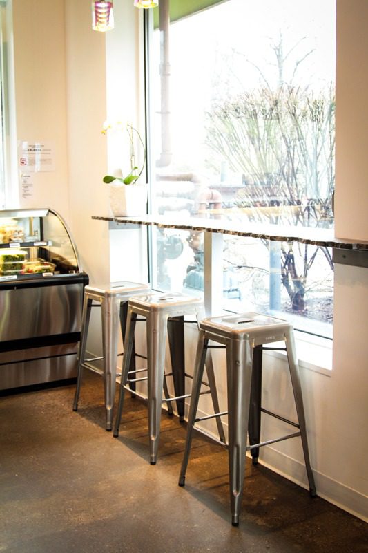 Minimalist kitchen with metal stools and natural light from large windows.