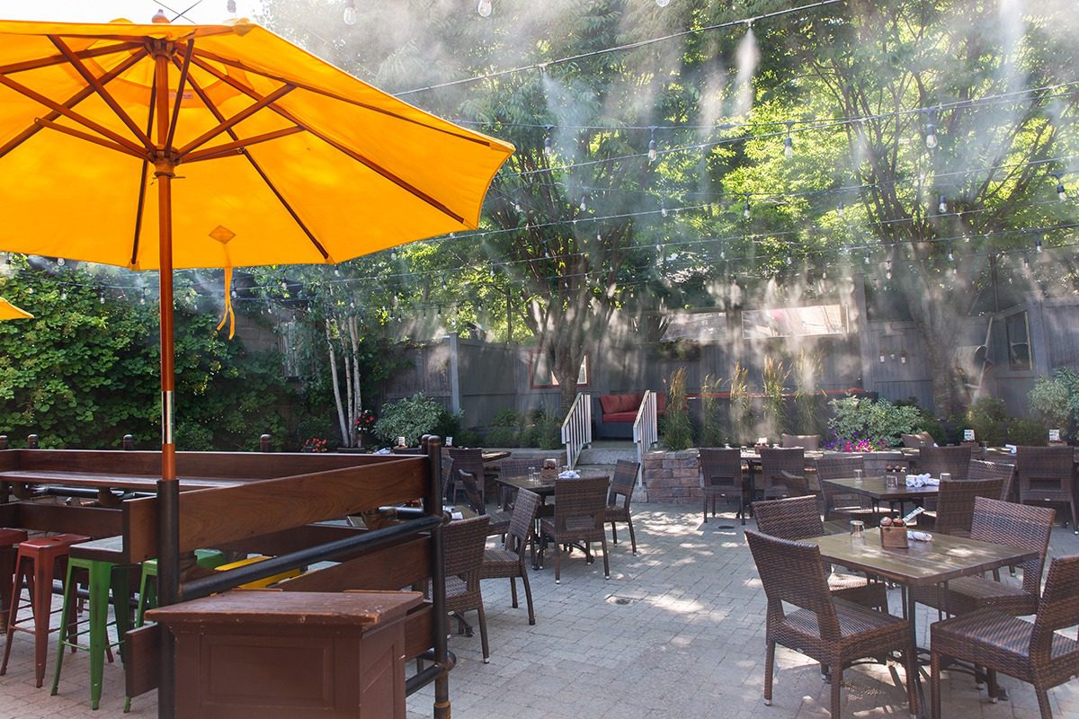 Outdoor seating area with wooden tables and a bright yellow umbrella.
