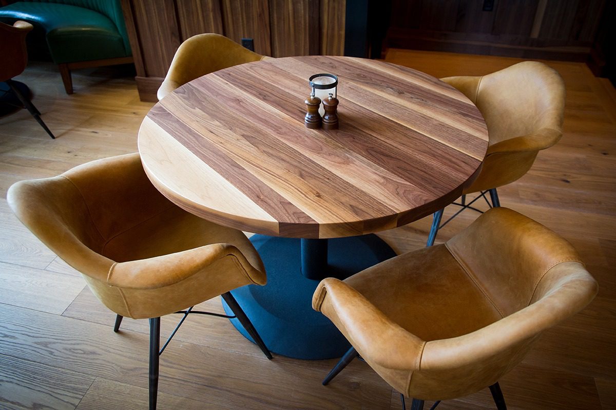 Round wooden table with leather chairs and a salt shaker centerpiece.