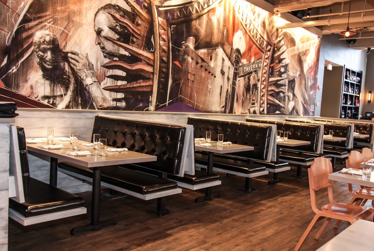Cozy restaurant interior with black and white booth seating and artistic wall murals.