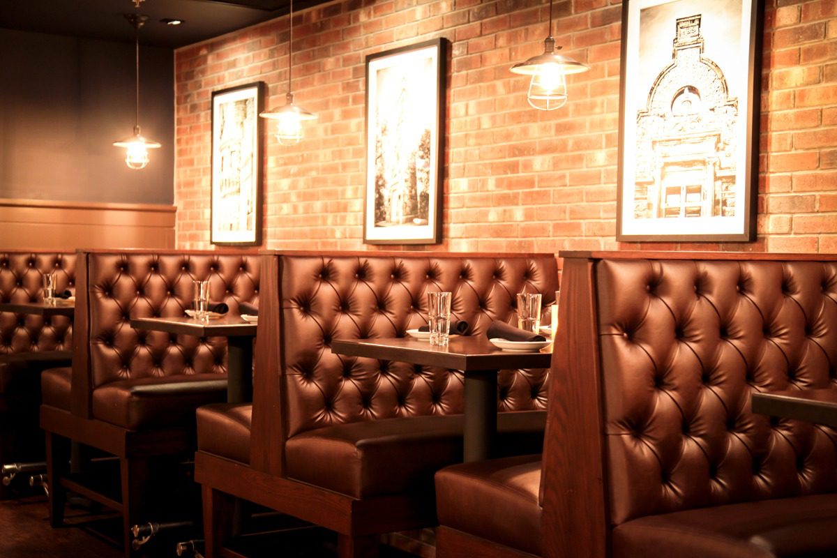 Cozy leather booths with warm brick walls in a stylish restaurant.