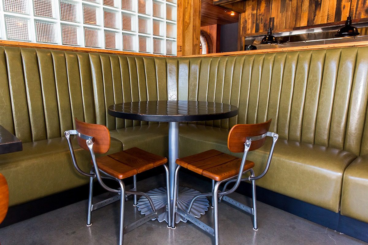Cozy booth with vintage metal chairs and a round table in a rustic café.