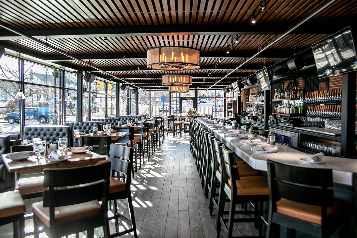Modern restaurant interior with wooden ceiling and ample seating.