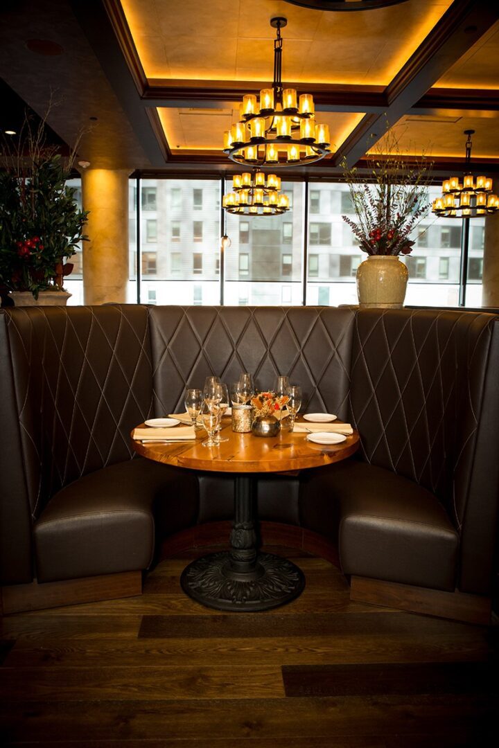 Cozy restaurant booth with a round wooden table and elegant lighting.