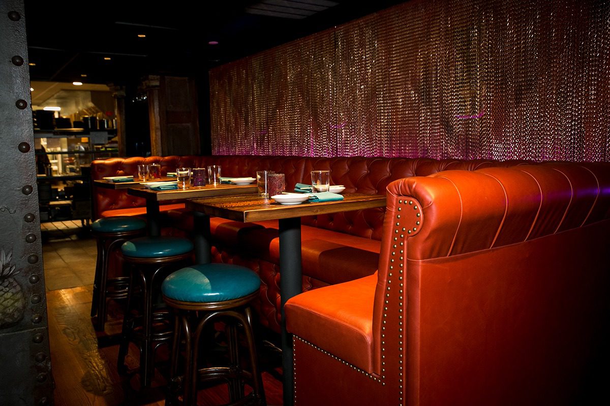 Cozy restaurant booth with red leather seating and warmly lit tables.