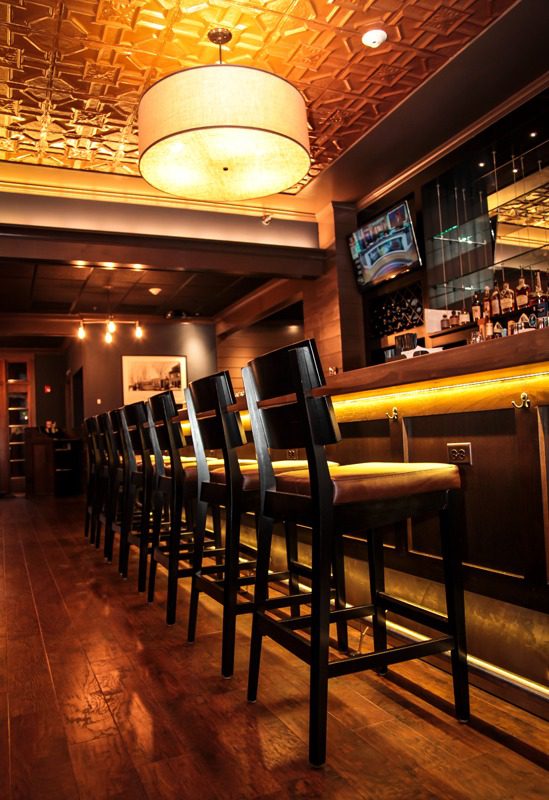 Cozy bar with high chairs and warm lighting.