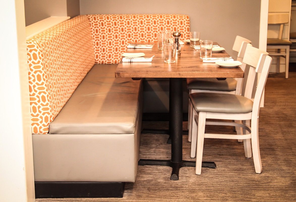 Cozy restaurant booth with cushioned seating and wooden tables set for dining.