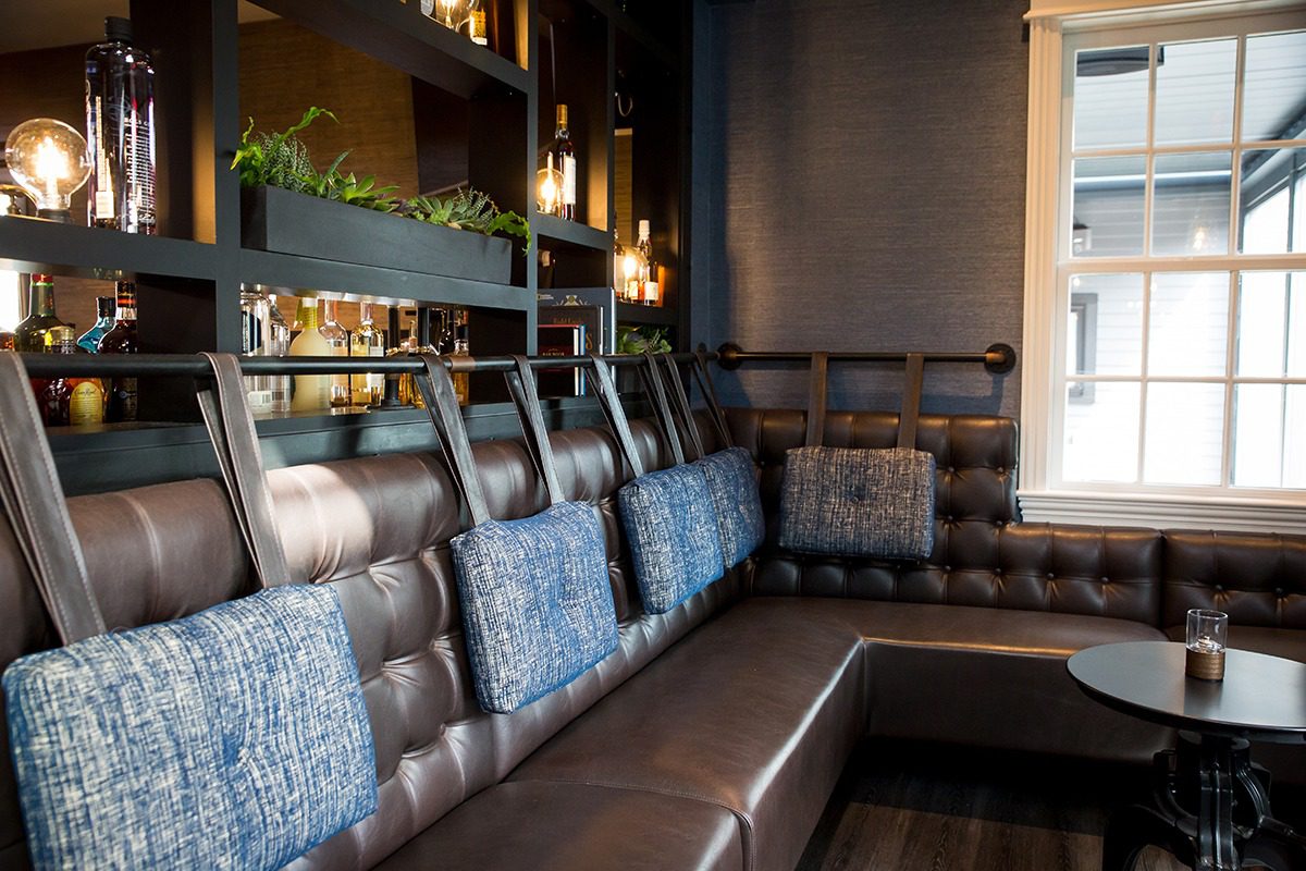 Cozy corner seating with tufted leather and patterned cushions in a warm lounge.