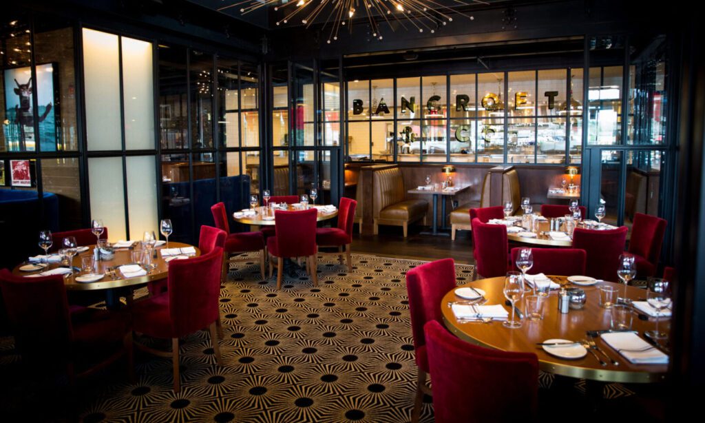Elegant restaurant interior with red chairs and stylish lighting.