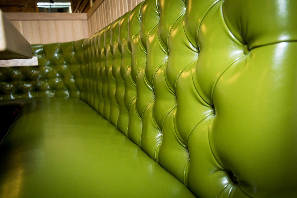 Close-up of a green tufted leather bench seat.