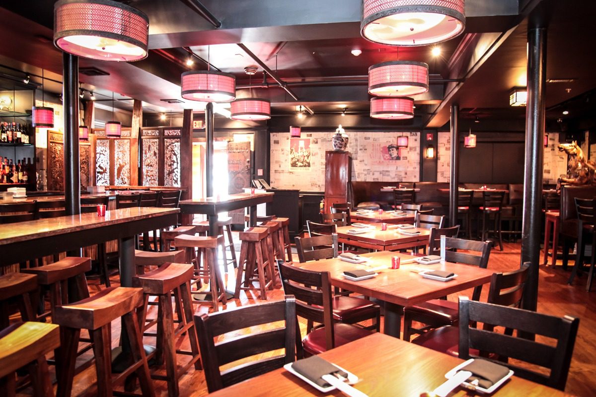 Cozy restaurant interior with wooden tables and chairs under warm lighting.