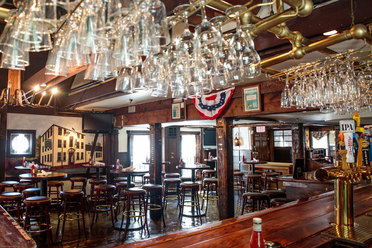 Cozy rustic bar with hanging glasses and wooden furniture.