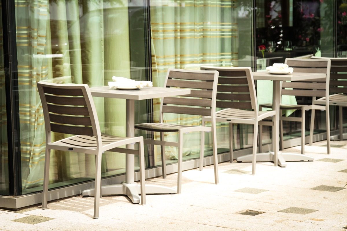 Empty outdoor café seating with modern chairs and tables.